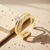 The golden double-layered ring features multiple round transparent gemstones on the upper layer and a large round transparent gemstone in the center on the lower layer. It has a white stone countertop Application Scenario